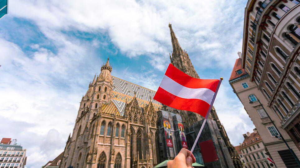 Saint Stephen's Cathedral on the central square in Vienna with the flag of Austria in female hands, Austria